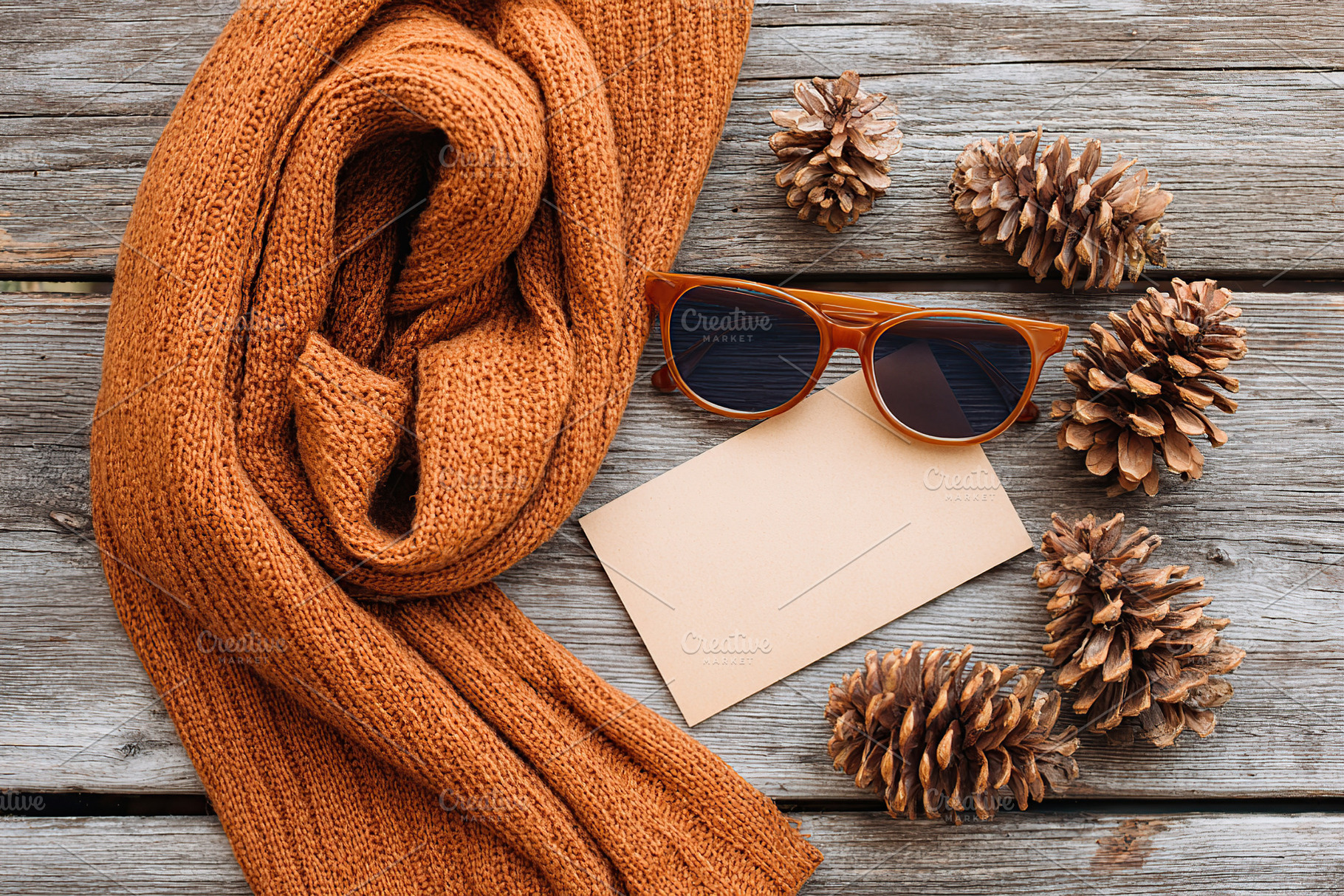 Vintage flat lay with a cozy scarf, sunglasses, and pinecones on rustic wooden, a Photo by AlyaAnd