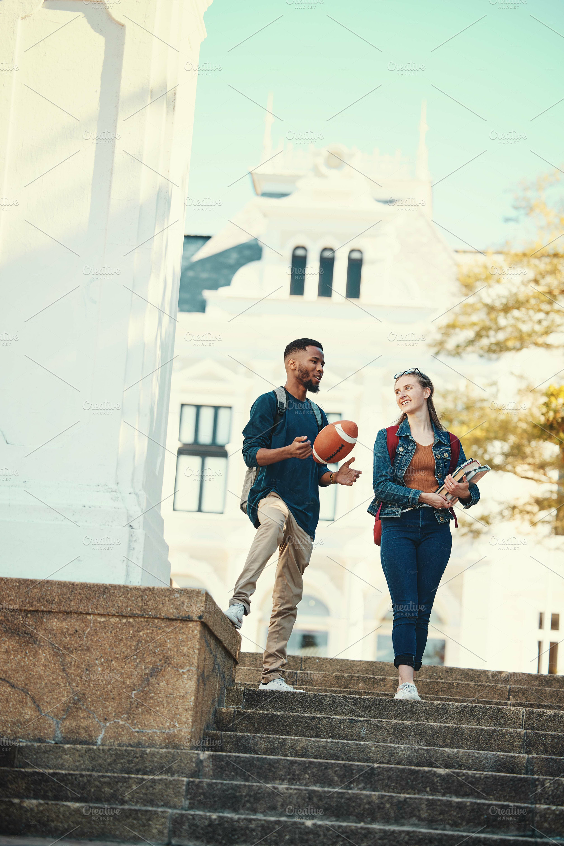 University, students and friends with a woman and man walking down stairs on campus for education. Learning, books and college with a male and female pupil taking a walk to class for studying, a Photo by Peopleimages.com