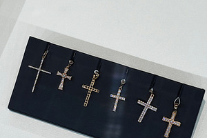 Collection of decorative cross pendants displayed on a dark background, a Photo by AS photostudio