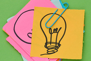 Stack of sticky notes with a light bulb drawn on them is held to, a Business Photo by ndanko