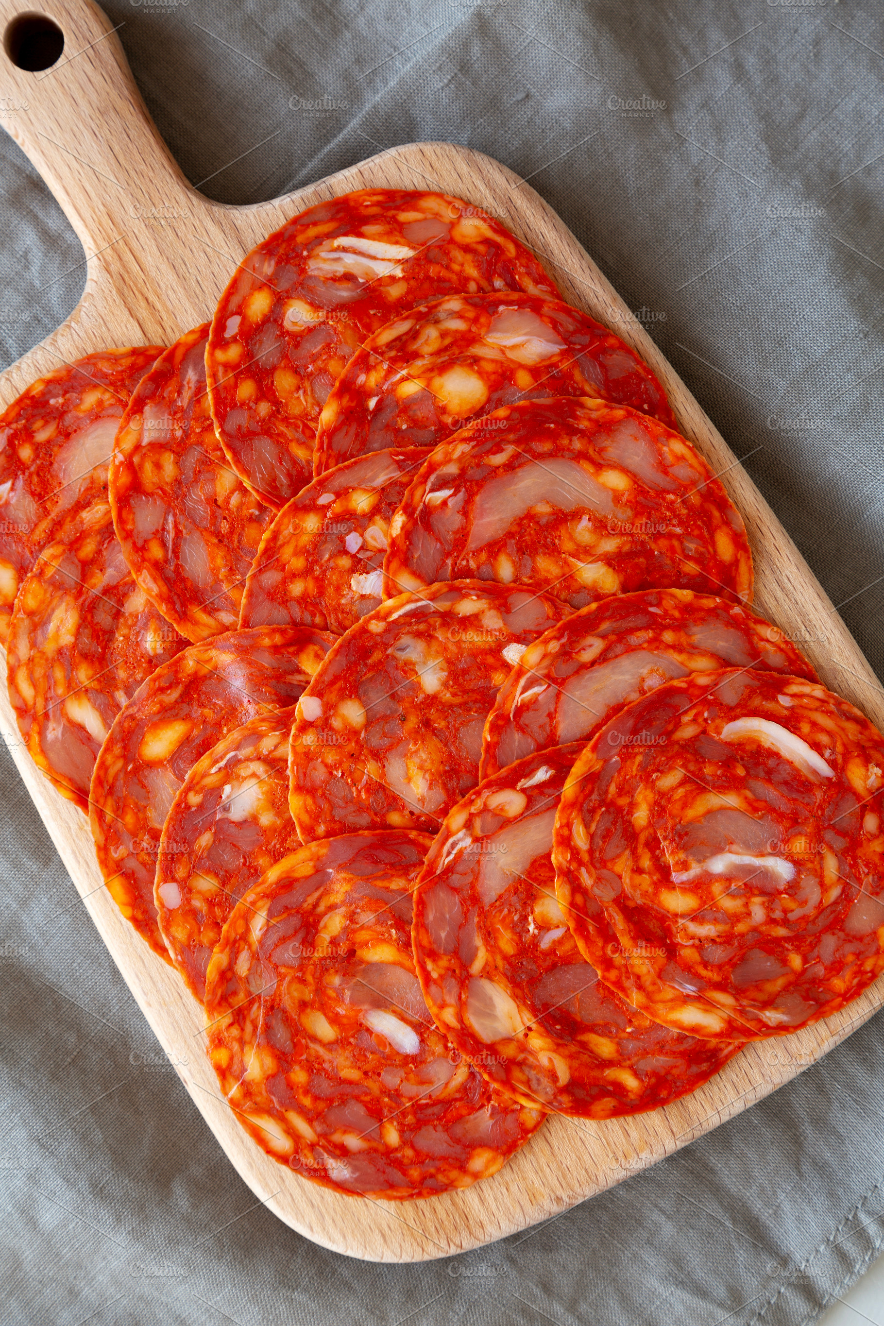 Cold Meat Chorizo Slices on a Wooden Board, top view., a Food & Drink Photo by LiudmylaChuhunova