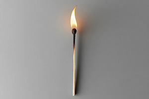 Ignited matchstick on grey background, a Photo by AlyaAnd
