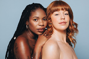 Two young women with different skin tones looking at the camera