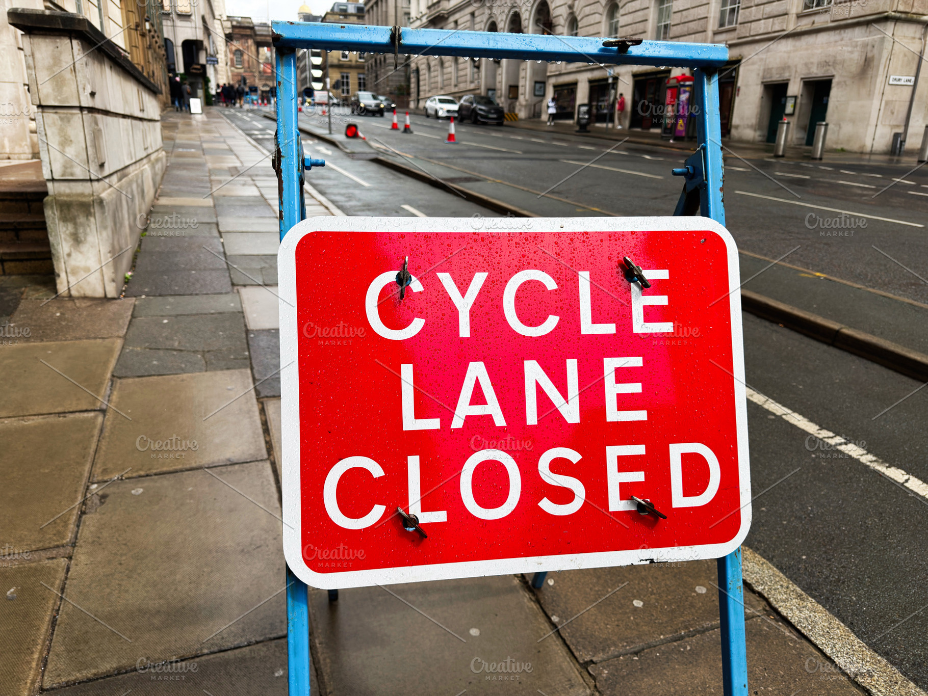 Cycle lane closed sign on wet street in Liverpool UK with blue f, a Photo by AS photostudio