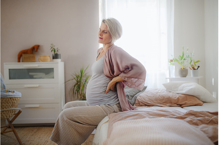 Pregnant woman sitting on her bed, a Person Photo by HalfPoint