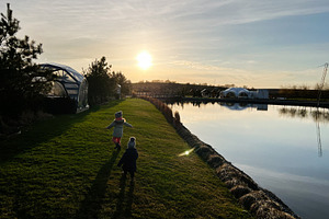 Children playing near a serene lake during sunset amidst nature's beauty, a Photo by AS photostudio