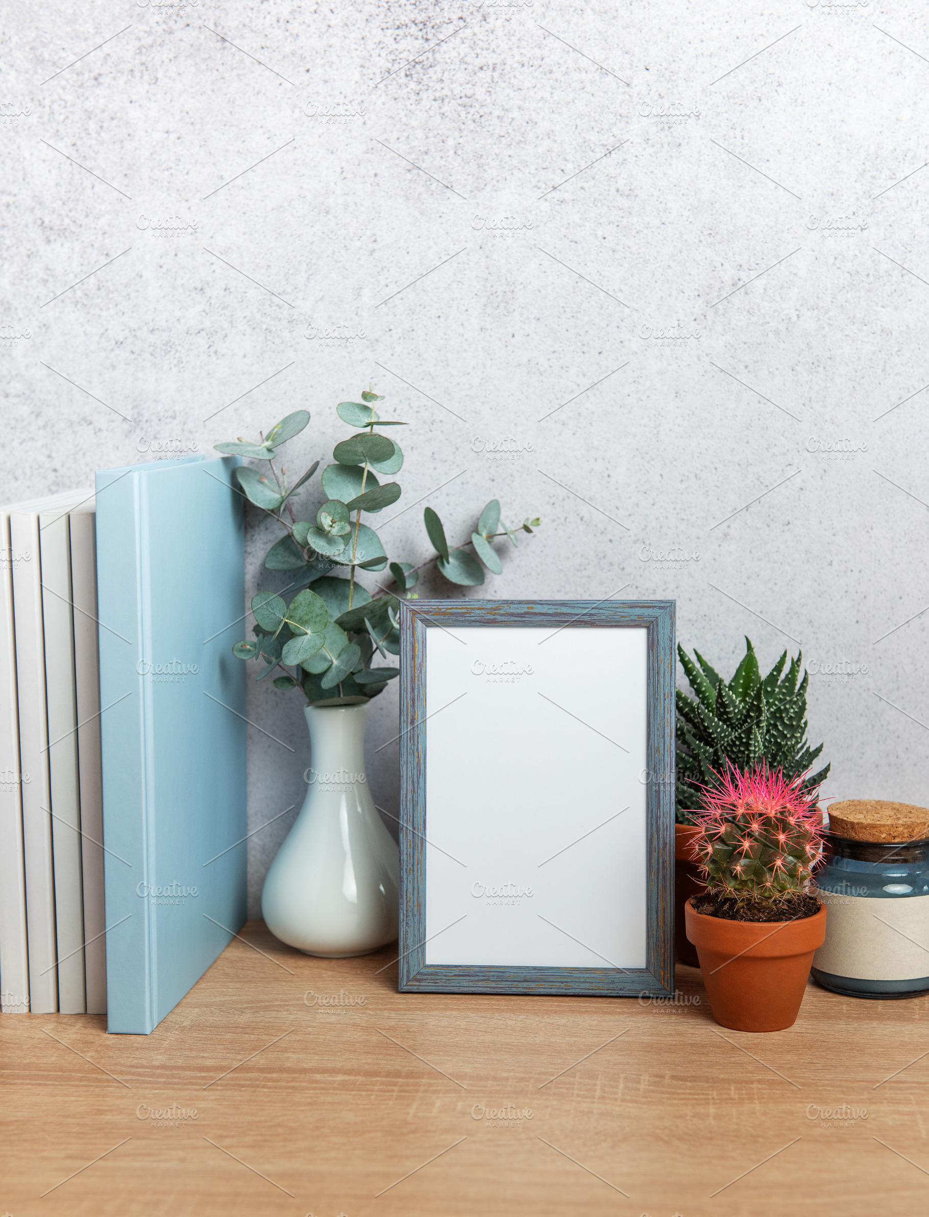 Blue picture frame standing on wooden desk with plants and books, a Background Photo by Olena Rudo