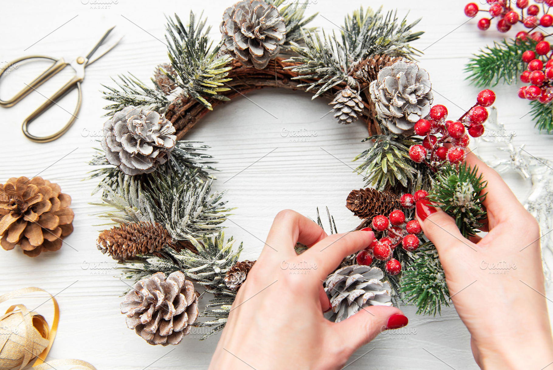 Hands decorating christmas wreath with pine cones and evergreen, a Holiday Photo by Olena Rudo