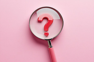 Magnifying glass focuses on a red question mark on a pink background, a Photo by AlyaAnd