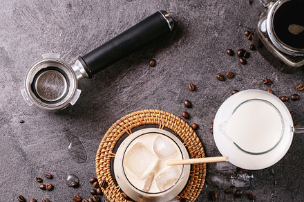 Glass of ice coffee with ice cubes served with cream