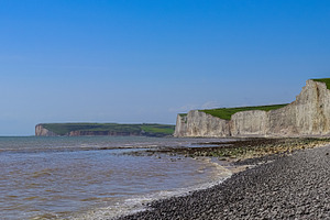 Seven Sisters cliffs towering over the pebble beach and incoming tide in East S, a Photo by Studio ANNA