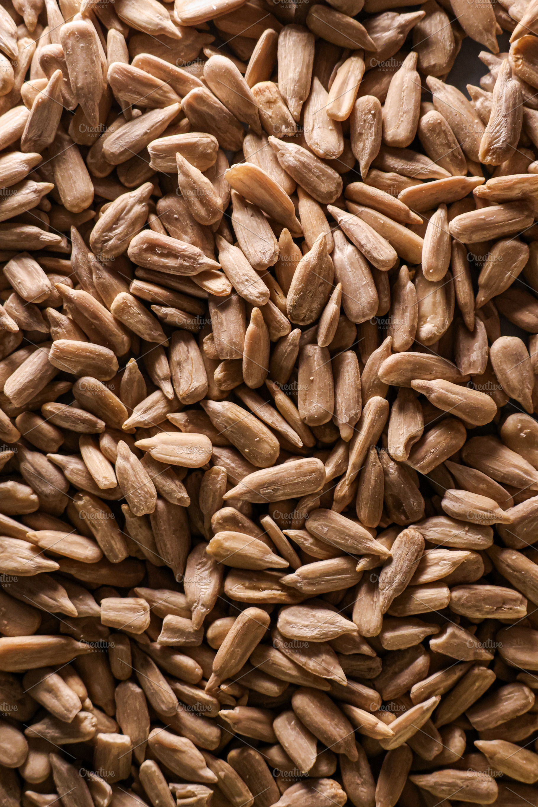 Peeled sunflower seeds filling the frame, creating a rustic background texture, a Photo by Studio ANNA