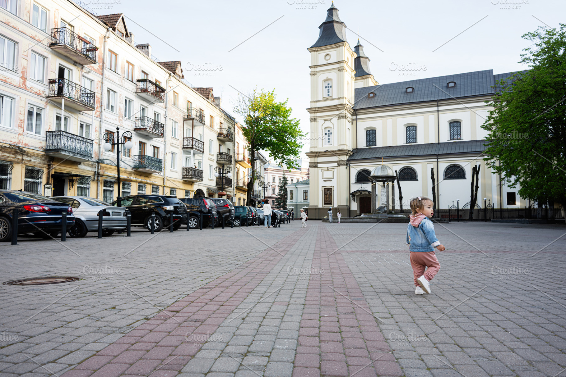 Child exploring an urban square with historic buildings and parked cars, a Person Photo by AS photostudio