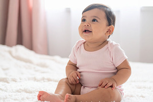 Baby girl sitting on a soft blanket in a bright room, a Person Photo by DanFLCreativo