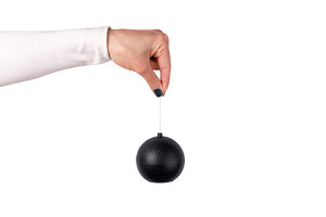 Black toy bomb held in female hand isolated on white background., an Abstract Photo by Ales Munt