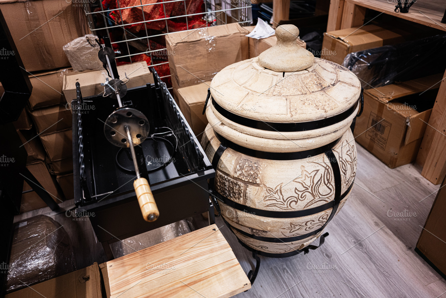 Clay oven and rotisserie barbecue set on display in a storage area, a Photo by AS photostudio