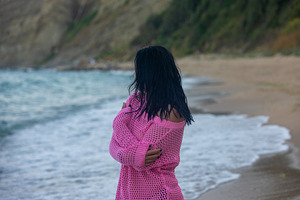 Woman in a pink sweater standing on sandy beach, looking at the sea, relaxed at, a Person Photo by Ales Munt