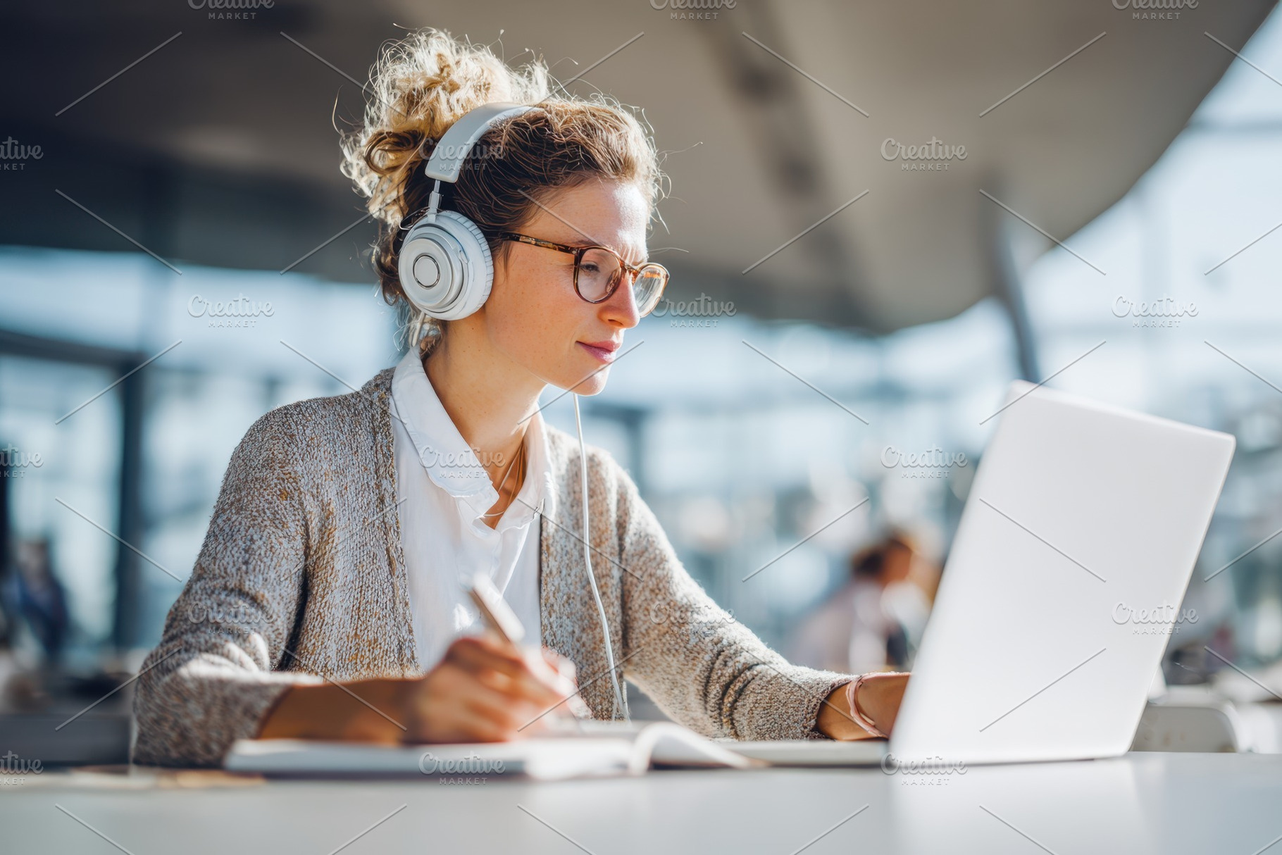 Woman working on laptop with headphones in office, a Person Photo by AlyaAnd