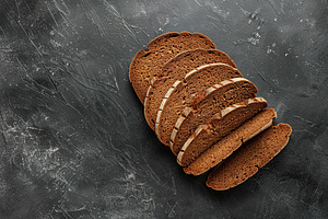Sliced baked rye bread on black background, a Food & Drink Photo by AlyaAnd