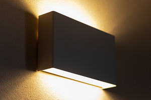 Modern wall lamp illuminating a textured wall, creating a warm ambiance, an Architecture Photo by Antonio Gravante Market