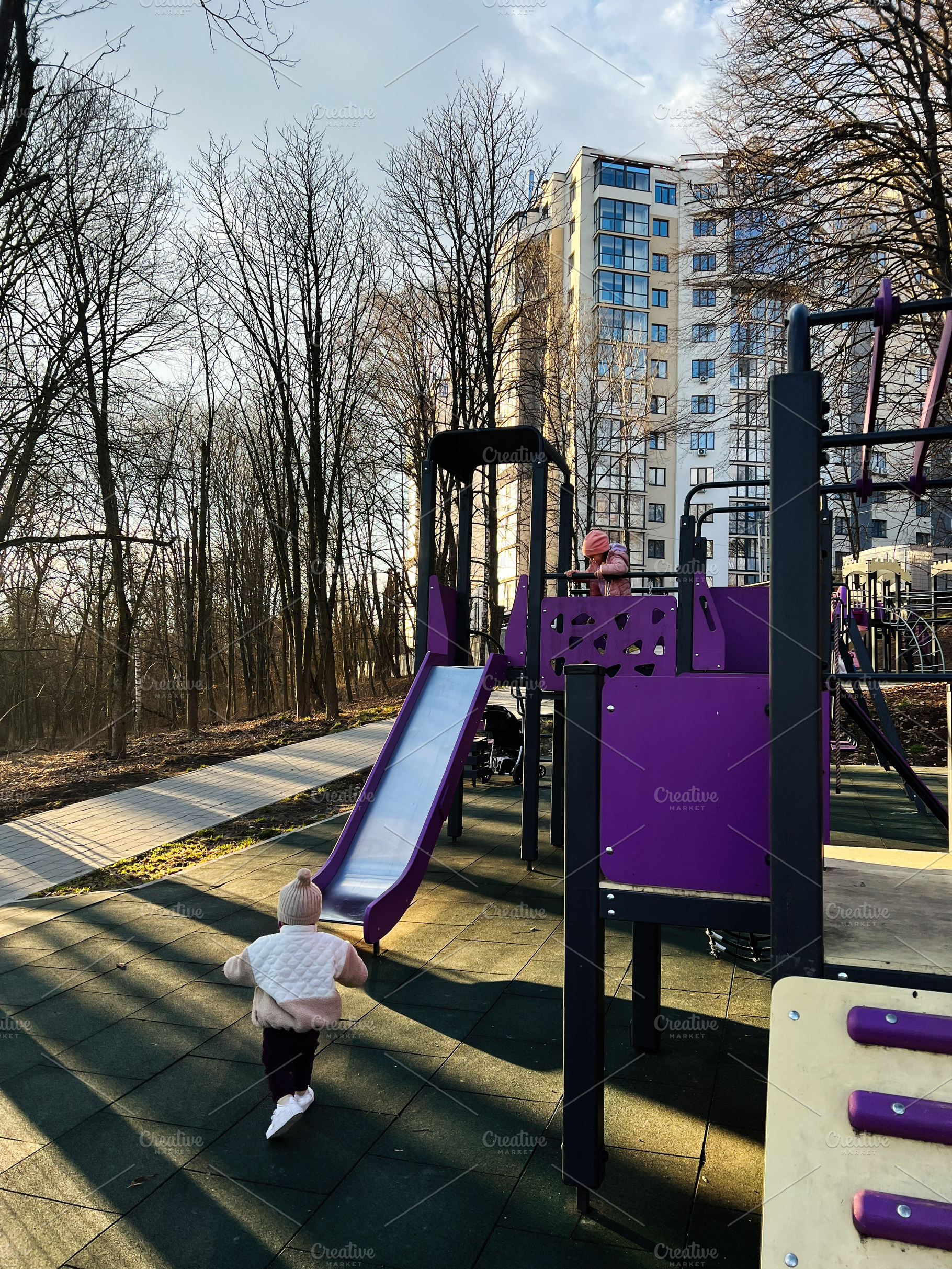 Children playing at a lively urban playground surrounded by trees and buildings, a Photo by AS photostudio