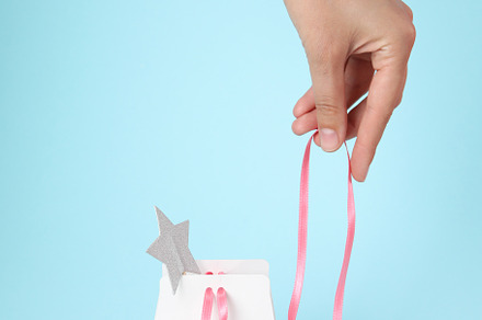 Concept of gift, female hand and gift bag on blue background, a Beauty & Fashion Photo by AtlasStudio