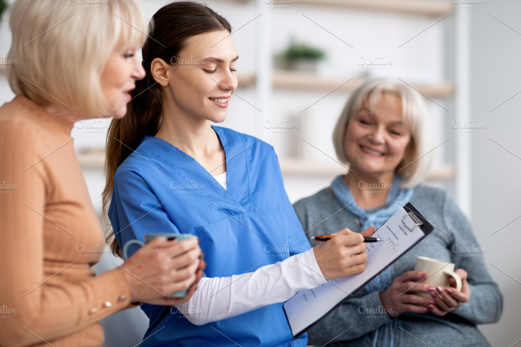 Friendly nurse questioning senior ladies at nursing home, copy space, a Photo by Prostock-Studio