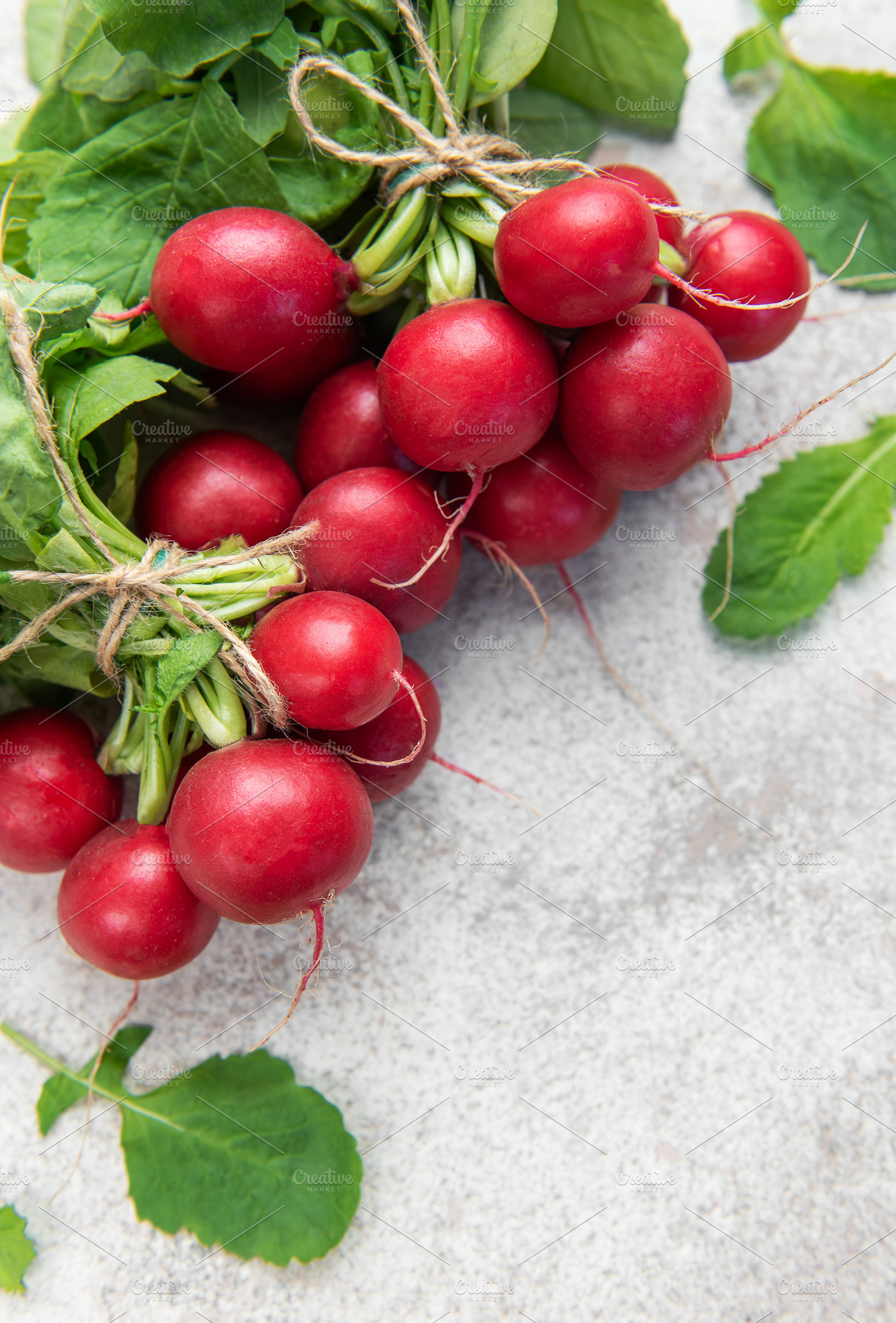 Fresh organic radishes with green leaves on light background, a Food & Drink Photo by Olena Rudo