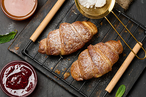 Baked croissants dusted with powdered sugar and apricot jam with, a Food & Drink Photo by ndanko