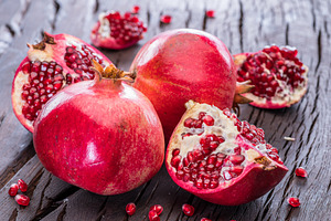 Ripe pomegranate fruits on the wooden background., a Food & Drink Photo by Volff