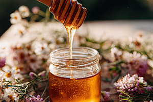 Close-up of a small glass jar filled with golden honey and wooden dipper on a r, a Food & Drink Photo by AlyaAnd