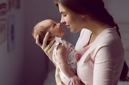 Mother in a white robe holds a small stock photo containing hold and health, a Person Photo by SaulichPhoto