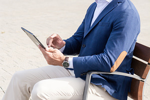 Businessman using digital tablet while sitting outside modern office building, a Photo by etorres69