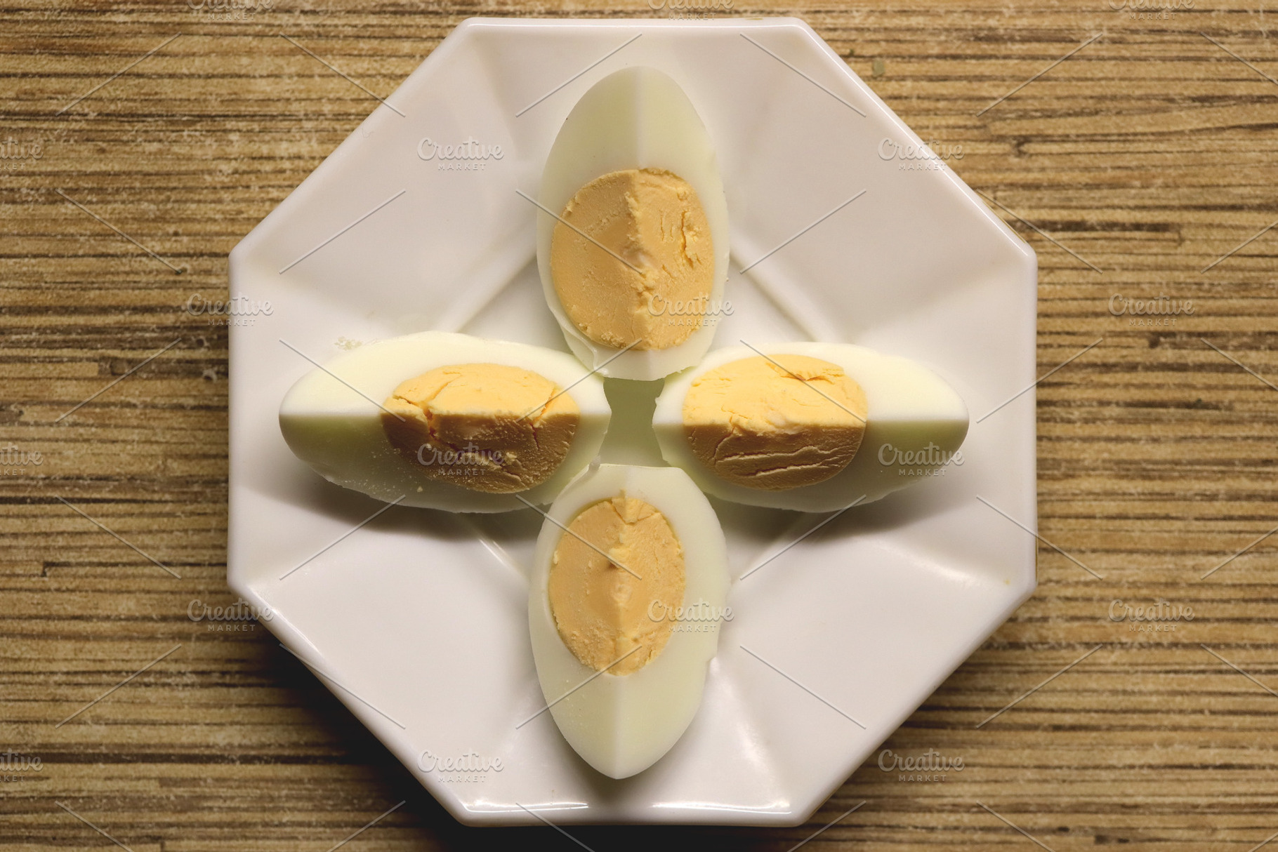 Four halves of hard-boiled eggs arranged on a white octagonal plate., a Food & Drink Photo by Textures & Backgrounds