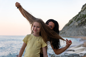 Smiling mother and daughter enjoying playful moments on a scenic beach during s, a Person Photo by Ales Munt