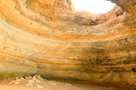 Coastal cave with golden cliffs and turquoise water. Sunlight st
