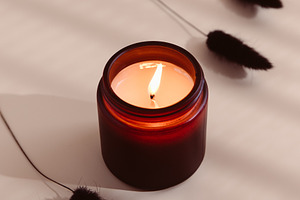 Burning candle in a dark amber glass, a Photo by Edalin's Store