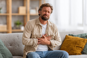 Man experiencing chest pain sitting, a Photo by Pixeness Studio
