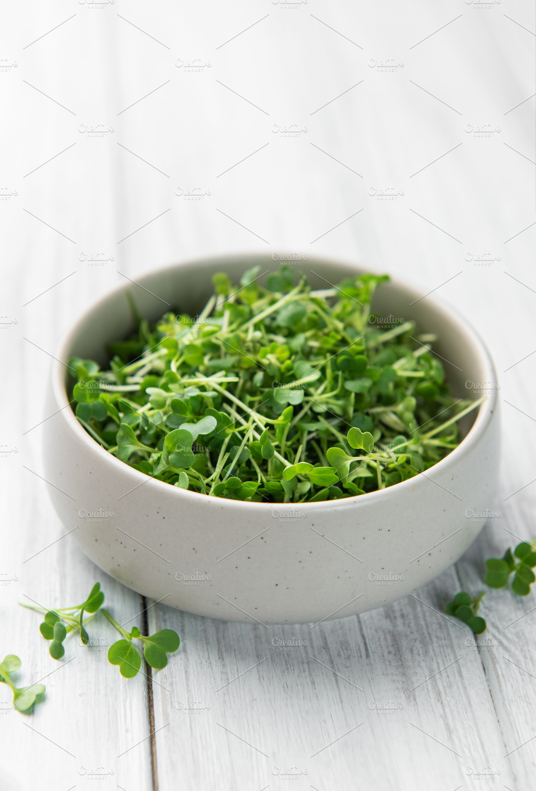 Fresh microgreens in bowl on white wooden table, a Photo by Olena Rudo
