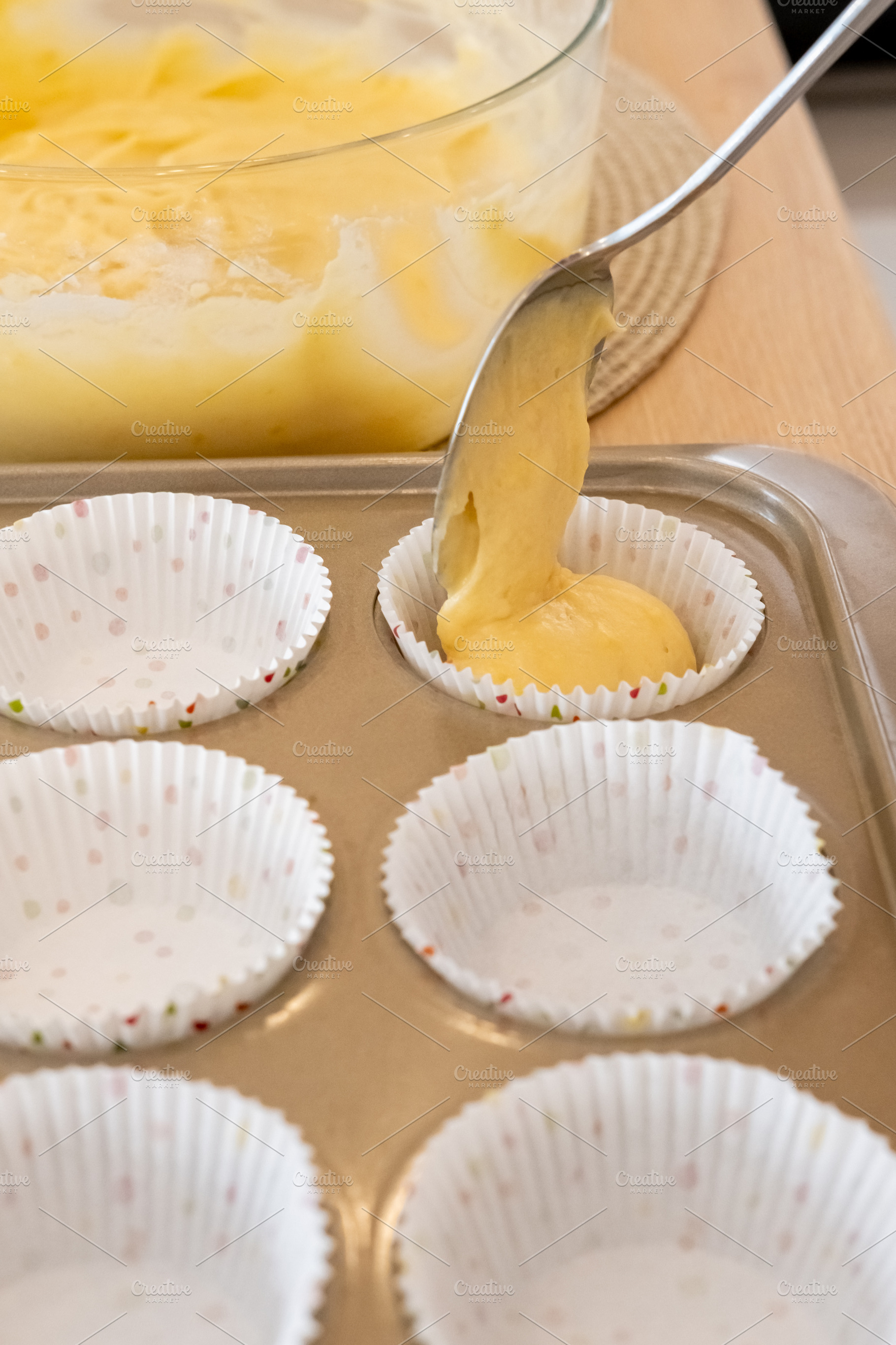 Preparing muffin treat recipe pouring batter spoon, a Food & Drink Photo by Photo Drive Studio