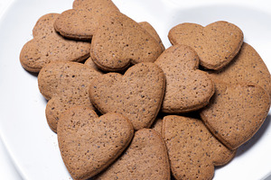 Heart-shaped gingerbread cookies on a white heart-shaped plate isolated on whit, a Food & Drink Photo by etorres69