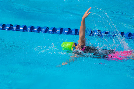 Swimmer child swims backstroke swimming style in a race swimming