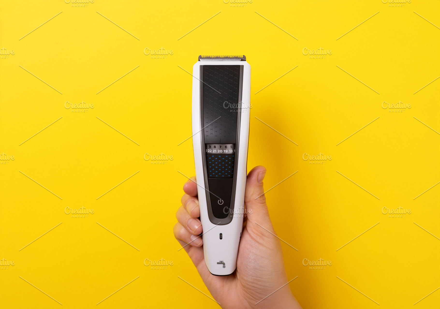 Close-up of hand holding a modern electric hair trimmer vertical, a Technology Photo by Ales Munt