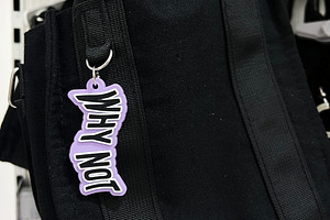 Black tote bag featuring a stylish keychain Why Not displayed on a retail shelf, a Photo by AS photostudio