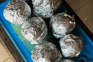 Foil Wrapped potato Arranged on a Blue Surface with Tiled Background, a Photo by AS photostudio