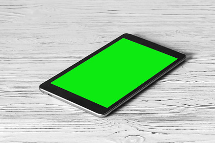 Black tablet with green screen on a wooden table mock up. Copy s, an Abstract Photo by Eugene_Photo