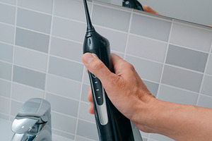 close view of a man lifting an oral irrigator, a Photo by Nito