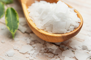 Magnesium chloride flakes on wooden spoon with green leaves, a Health & Medical Photo by Olena Rudo