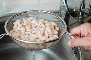 rinsing white beans in the kitchen sink, a Photo by Nito