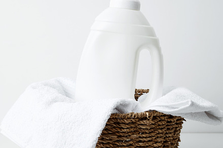 Laundry detergent branding mock up and basket filled with clean white towels. H